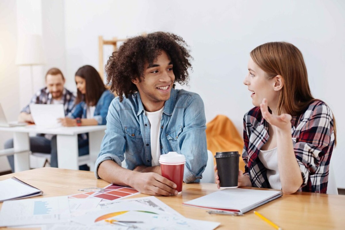 Two young people discussing ideas over coffee at a workspace